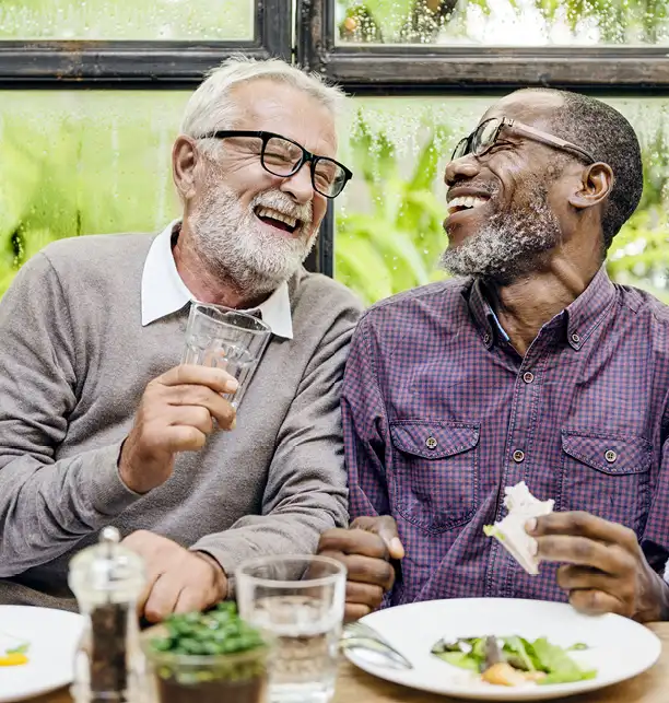 Two senior men laughing while enjoying lunch