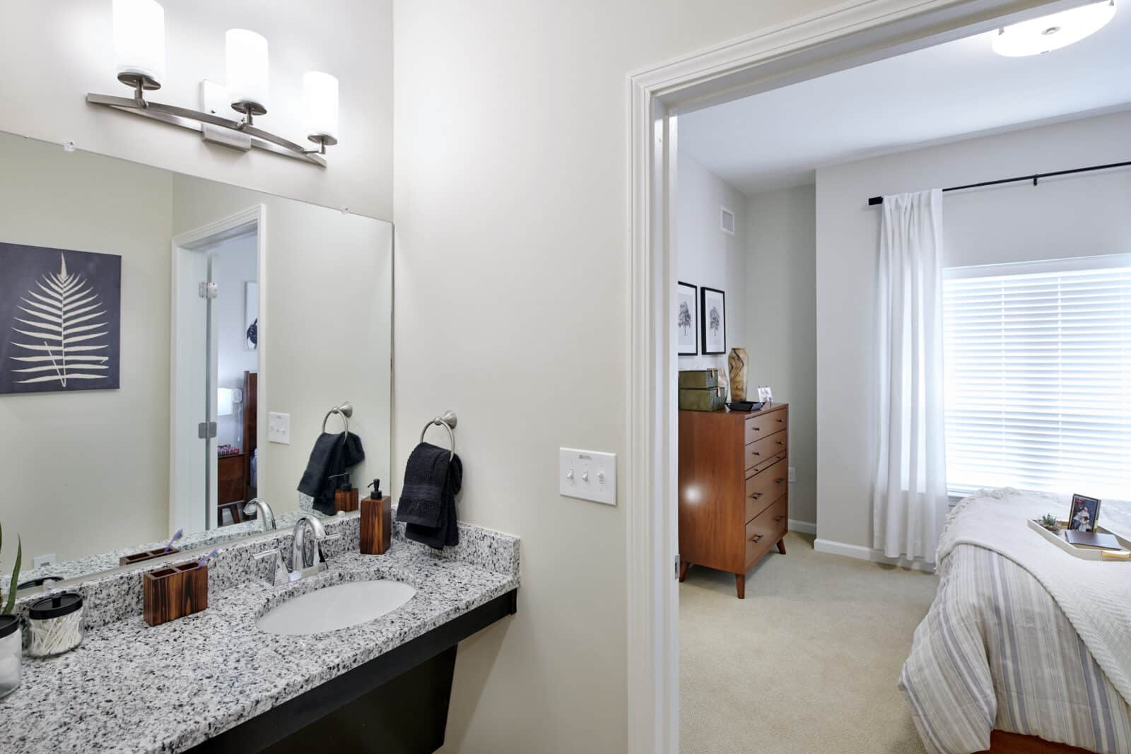 bathroom vanity with sink and hand towels; adjacent bedroom