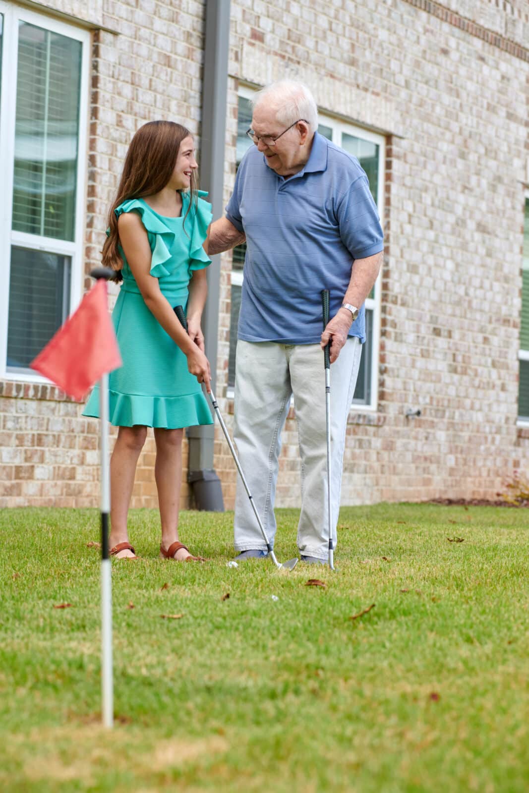 resident showing his granddaughter how to hold a golf club